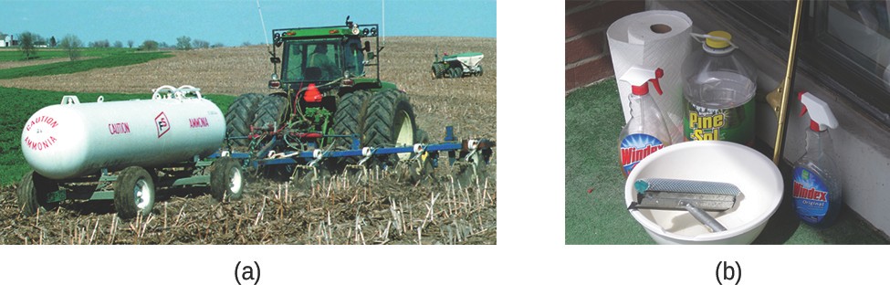 This photograph shows a large agricultural tractor in a field pulling a field sprayer and a large, white cylindrical tank which is labeled “Caution Ammonia.”