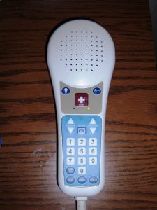 “Hill-Rom_hospital_bed_TV_remote_control.JPG” by BrokenSphere is licensed under CC BY-SA 3.0 Photo showing closeup of a patient's call light