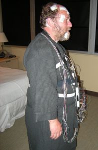 “Wired_up_for_a_sleep_study_02A.jpg” by Joe Mabel is licensed under CC BY-SA 3.0 Image showing patient wired up for sleep study