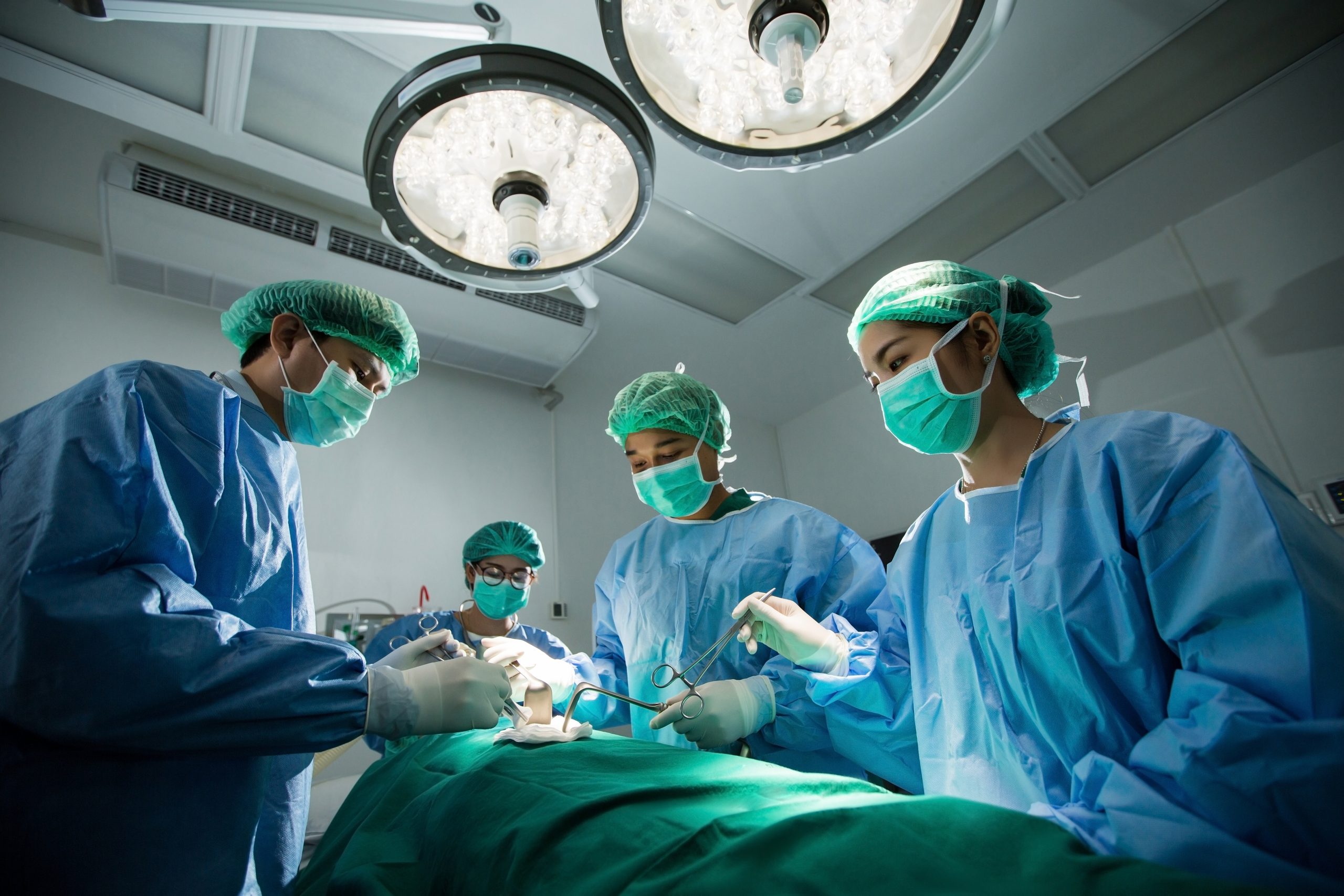 "226589236-huge.jpg" by TORWAISTUDIO is used under license from Shutterstock.com Image showing masked medical team surrounding a patient in a surgical theater