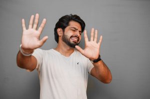 “Young-indian-with-disgusting-expression-showing-denial-with-hands-42509-pixahive.jpg” by Sukhjinder is licensed under CC0 Image showing a man, facing camera, with pained expression and hands up in a defensive position