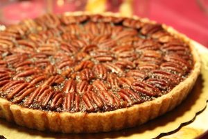 Image of a pecan pie on a gold table with a red background.