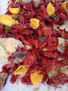 Image of a crawfish boil with whole crawfish, sausage, and lemons.