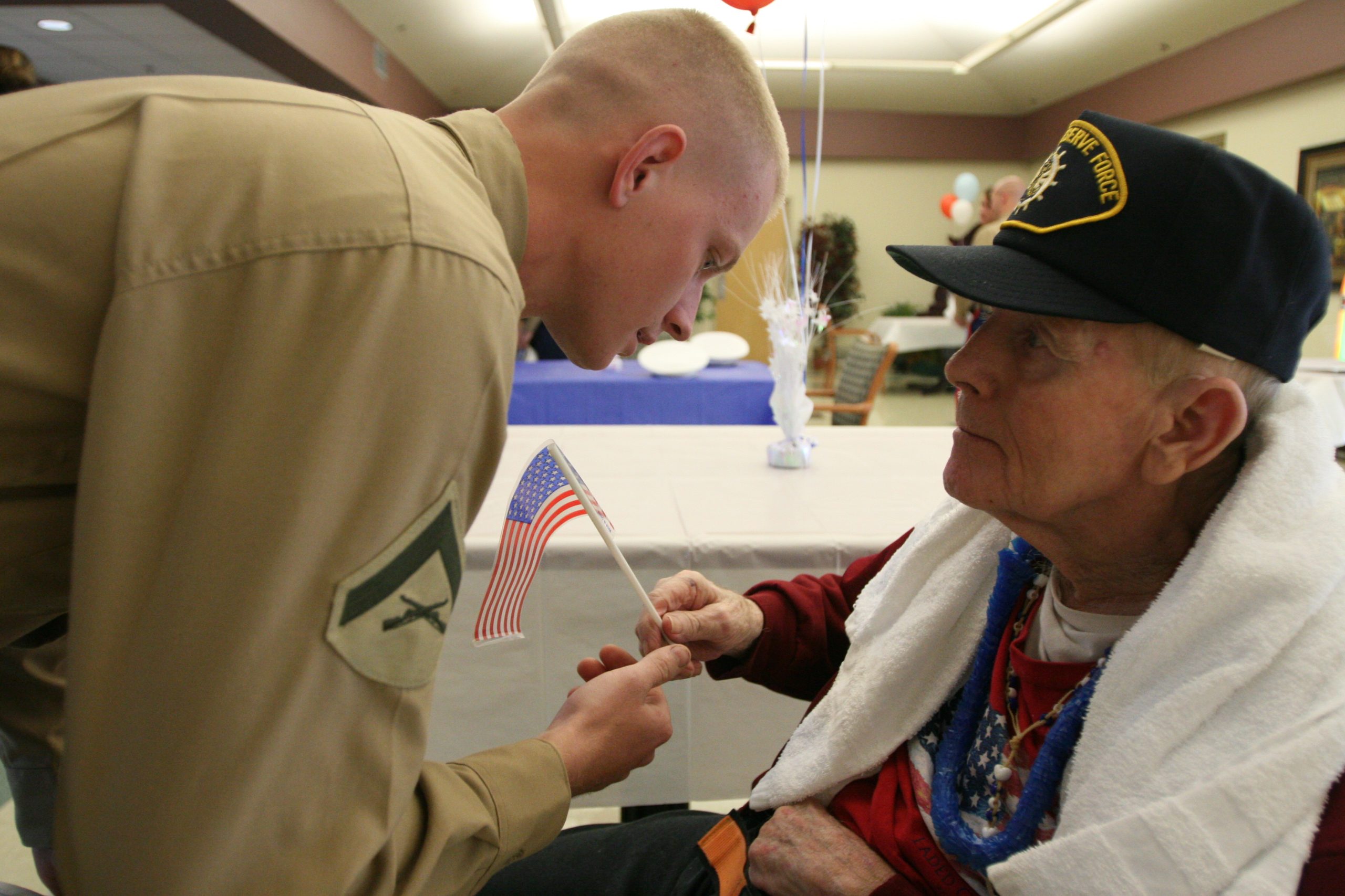 Lance Cpl. Dustin Reddell, administration clerk, Marine Forces Reserve Headquarters hands a small U.S. flag to an elderly veteran at the Southeast Louisiana War Veterans home in Reserve, Louisiana.