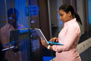 Black lady looking at a laptop in front of servers
