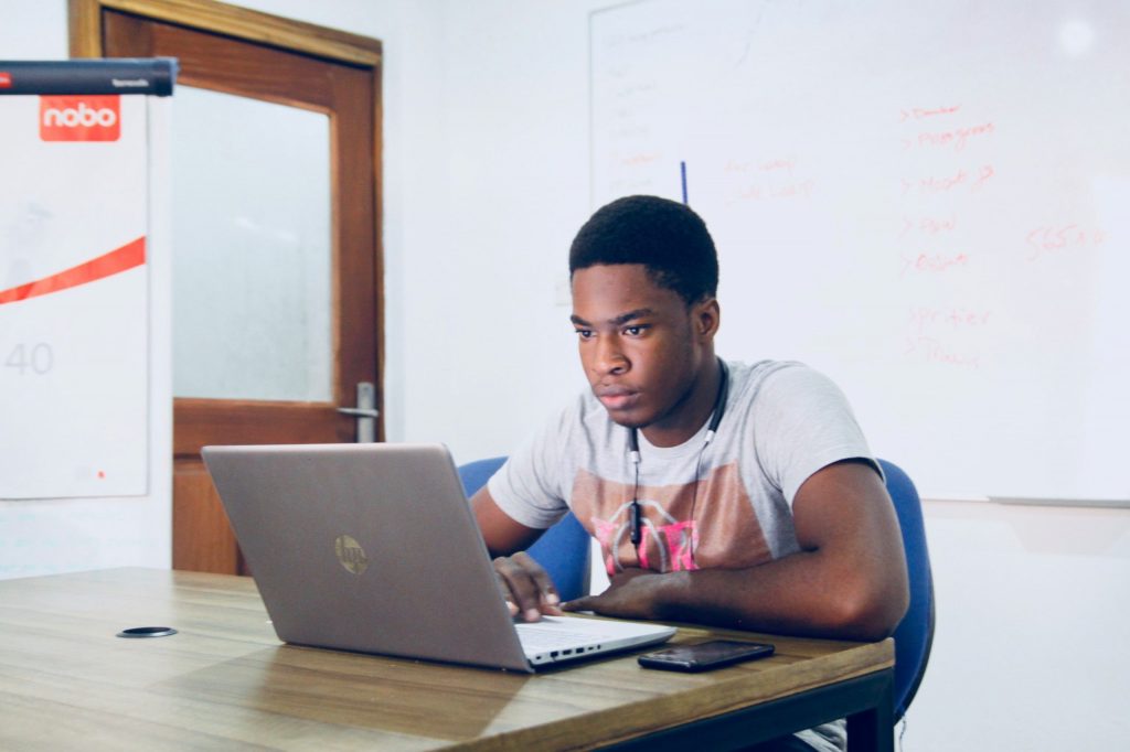 Black Man sitting looking at a laptop
