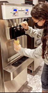 A woman serving soft serve ice cream from a macine
