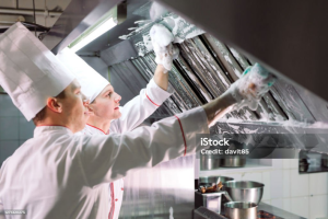 Kitchen employees cleaning the hood vent
