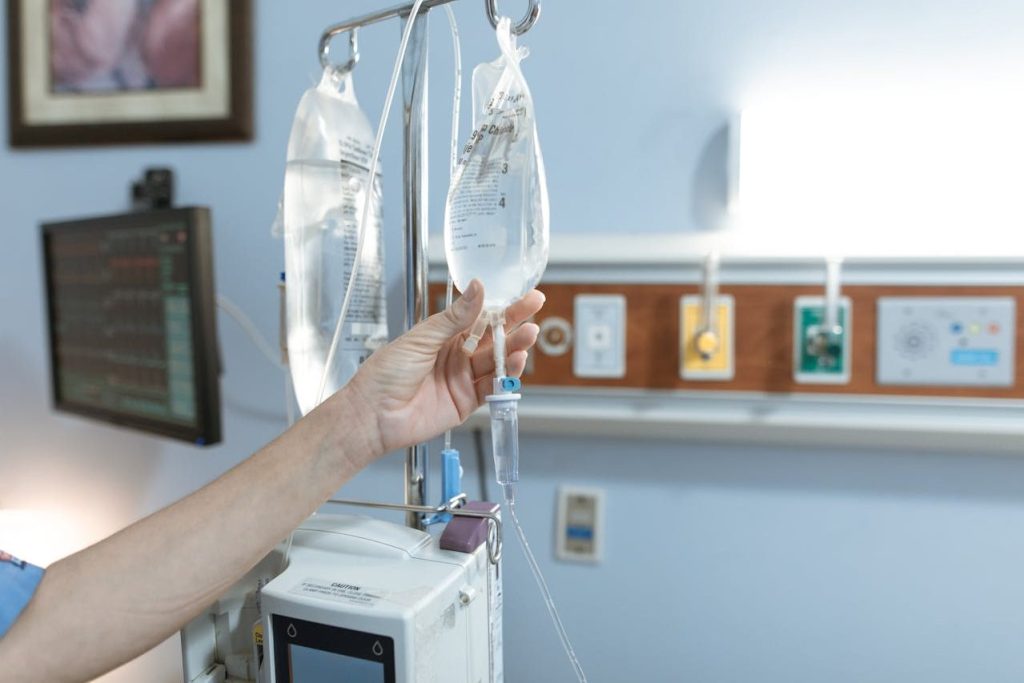 a nurse's hand is seen gently squeezing a packet of dextrose solution hanging on an IV stand