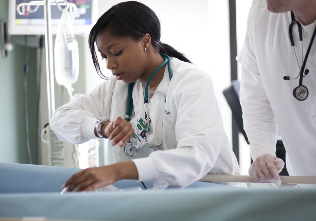 Nurse checking watch while taking patient's vitals