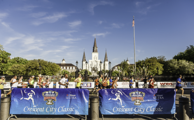 Runners participating in the Crescent City Classic marathon, with Jackson Square and St. Louis Cathedral in the background.