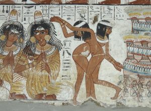Fragment (one of three) of a polychrome tomb-painting representing a banquet scene, divided into two registers: upper - men and women sit together and are attended by one standing servant-girl; lower - four musicians (two shown full-face) are shown seated on the ground while two dancers provide entertainment for the guests, fifteen vertical registers of hieroglyphs survive.