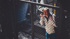 Person standing behind a chain-link fence in an industrial setting.