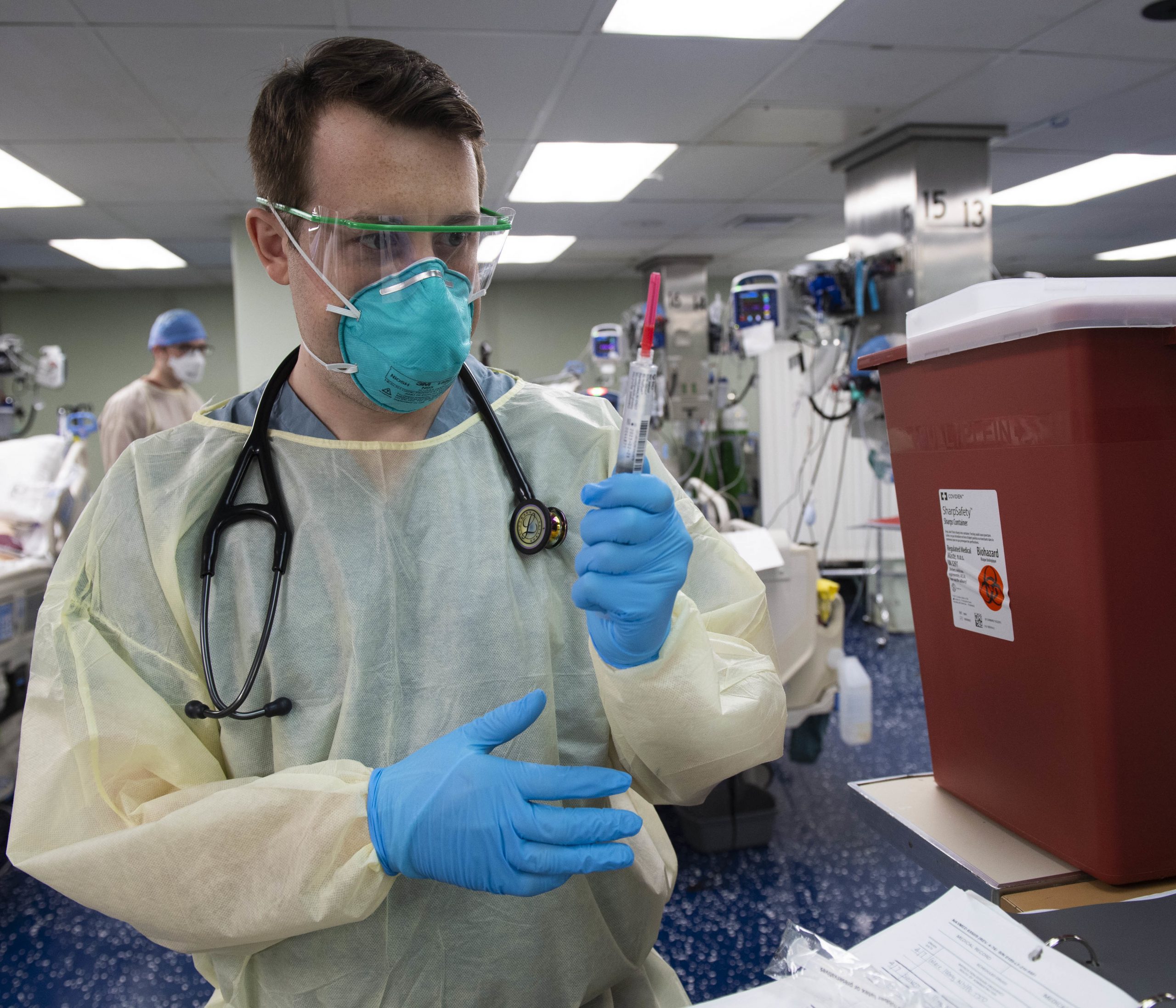Photo of man wearing PPE holding a syringe