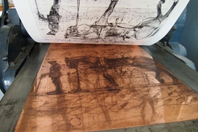 An intaglio print being pulled from a copper plate.