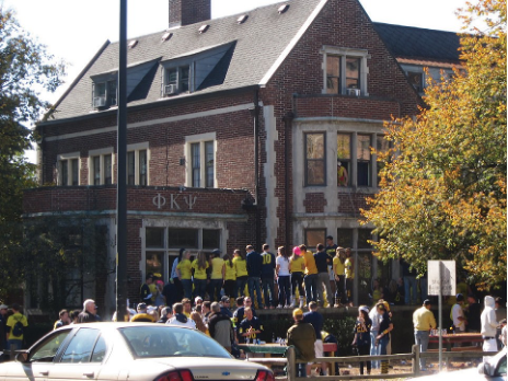 Several college students outside participating in a fraternity pledging activity.