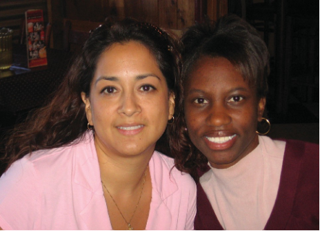 Two women smiling. One lighter skinned and one with darker skin.
