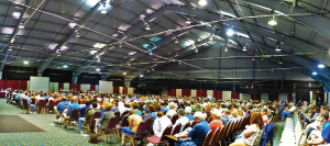 Large group of people sitting in chairs inside of a large room.