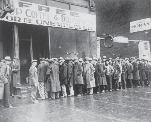 Line of people in long coats and hats standing in line outside a building.
