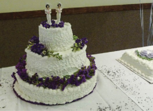 Cake with three tiers. Two human figurines appear on the top tier.