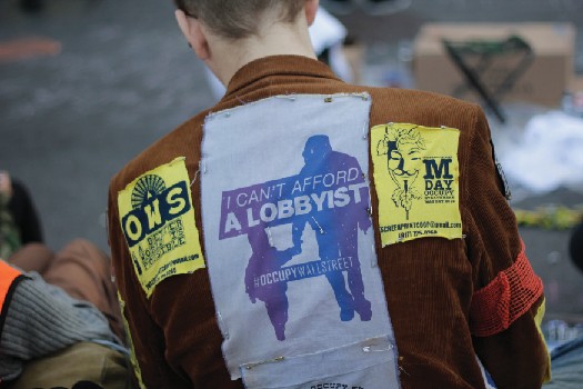 Back a person wearing a jacket with several patches.