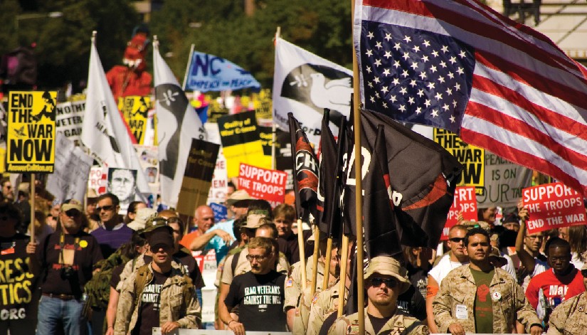 Group of people, several of whom are holding flags and signs.
