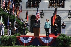 Barack Obama speaking outside the White House. Standing next to him is Angela Merkel.