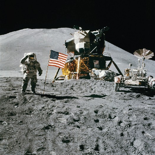 Astronaut on the moon standing next to the American flag.