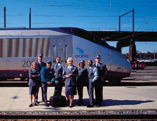 Amtrak staff standing on a train platform as a train passes behind them.