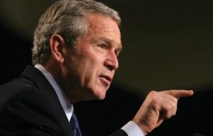 George W. Bush in profile, pointing his finger to the right.