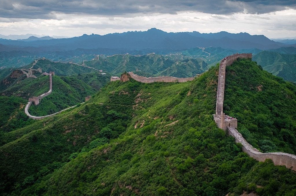 A long stone wall spanning the tops of green mountains at Jinshanling