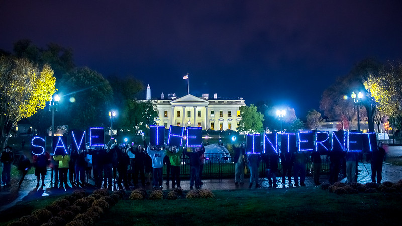 Protestors outside of the White House holding up lit letters that spell out "Save the Internet"