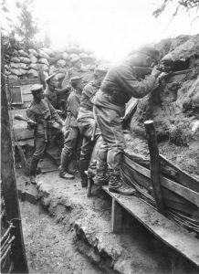 Five German soldiers fighting from a trench, one is shooting a gun while another is throwing what appears to be a grenade