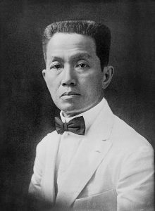Photographic portrait of Emiio Aguinaldo in white suit with black bowtie looking into camera