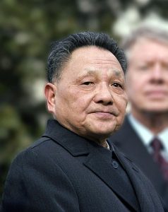 Colored photograph of Deng Xiaoping in black suit with US President Jimmy Carter blurred in backround