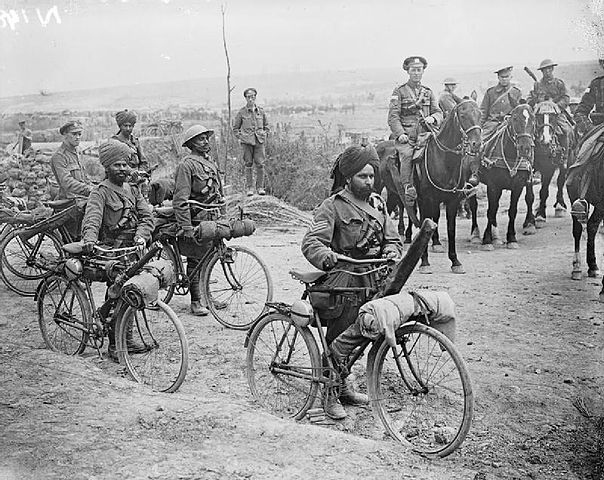 Indian bicycle troops walking their bikes with cavalry on horses behind them