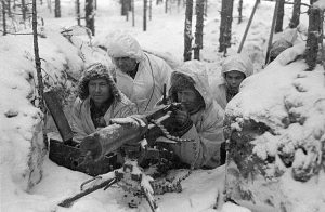 A group of Finnish soldiers in snowsuits manning a heavy machine gun in a snow-covered foxhole