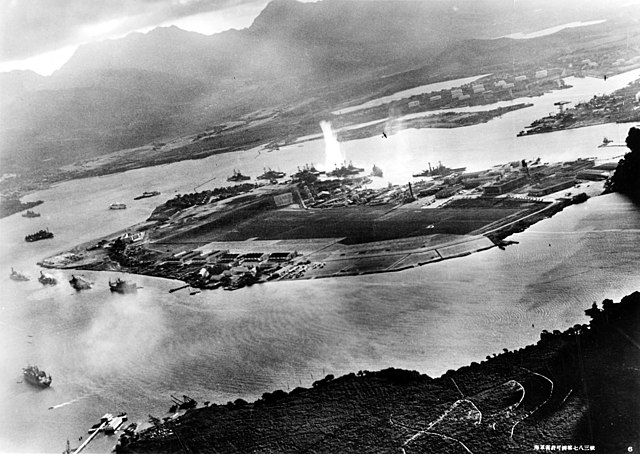 Aerial photograph taken from a Japanese plane of bombs exploding on Ford Island during the Pearl Harbor Attack with US battleships and other boats in the water