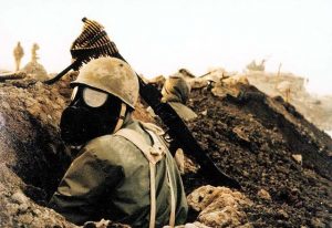 An Iranian soldier wearing a gas mask with machine gun in a trench during the Iran-Iraq War