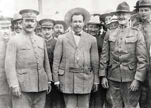 Pancho Villa (center) in suit flanked by Generals Obregon (left) and Pershing (right) meet in El Paso, Texas. Immediately behind Pershing on his left is his aide Lt. George S. Patton.