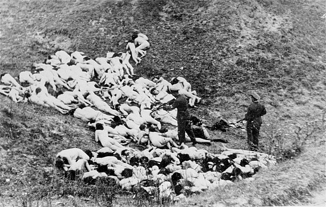 A pile of naked Jewish women with an officer raising a gun to shoot those who survived the initial shooting