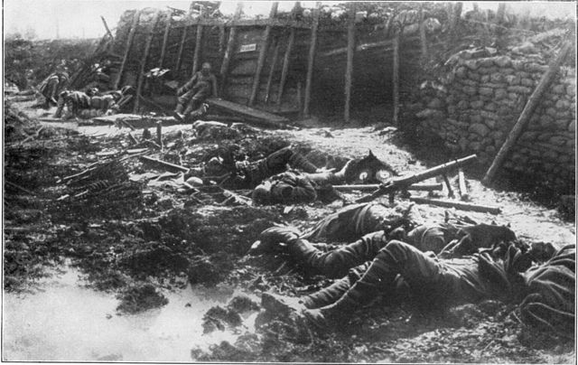 Numerous British soldiers lay dead in a trench surrounded by weapons after a German gas attack