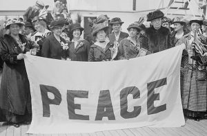 American women delegates to the International Congress of Women holding a large cloth sign that says "Peace"