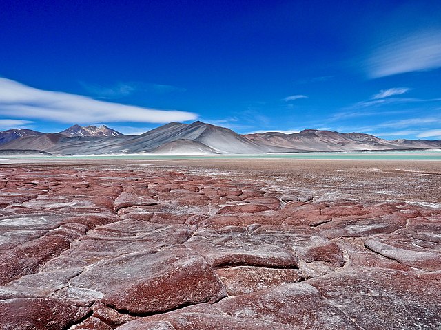 Dry desert plain with mountains and blue sky in distance