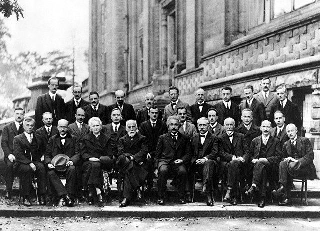 Men and one woman (Marie Curie) sitting for a photographic portrait with Albert Einstein seated in front middle