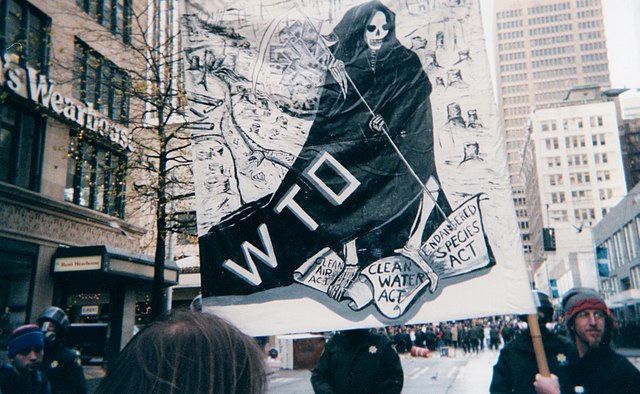 Protest banner with a skeleton in dark cloak with scythe as image of death with WTO on cloak