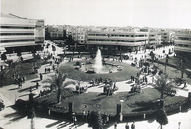 Zina Dizengoff Circle with fountain in the center surrounded by palm trees and buildings in Tel Aviv