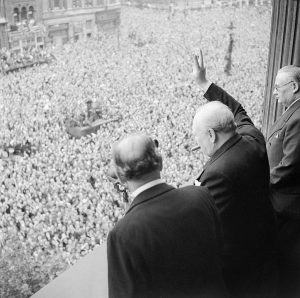 Winston Churchill showing the Victory sign to a large crowd gathered below