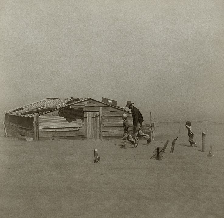 Farmer with two children walking towards a dilapidated building across sand during a dust storm