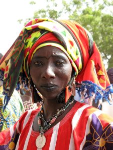 A woman in Burkina Faso in colorful clothing, jewelry, and head wrap